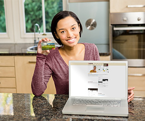 woman on computer holding up credit card