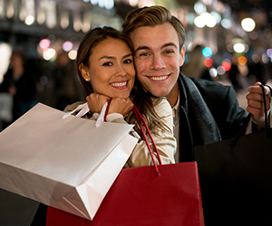 man and woman smiling and holding shopping bags