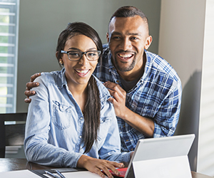 woman and man on tablet and smiling at the camera